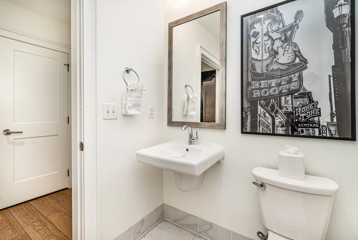 A stylish bathroom area featuring a modern sink, large mirror, and vibrant artwork on the wall. The design is both inviting and functional, suggesting thoughtful touches that enhance daily routines.