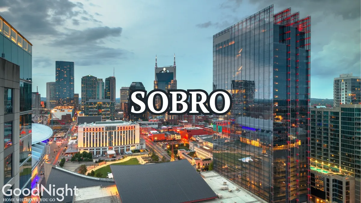 A nighttime view of Nashville's city skyline and river, with downtown lights twinkling and bustling streets below. The vibrant lights hint at the immersive nightlife and cultural events that pulse through the city after dark.